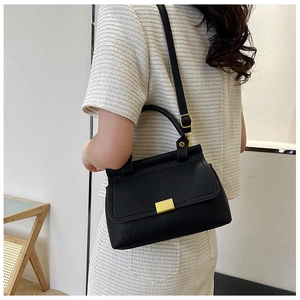 Chic black lychee leather handbag with gold buckle shown on a model in a modern outfit