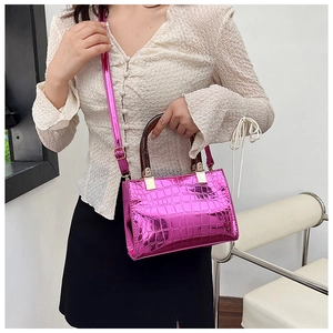 Detail of glossy metallic pink handbag with crocodile pattern and amber ring handle