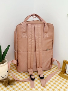 Detail view of the pink backpack back featuring adjustable straps and a safety zipper pocket