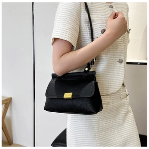 Close-up of black lychee grain leather handbag with elegant matte gold metal buckle detail