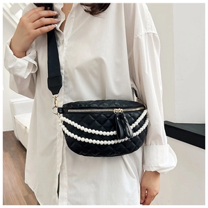 Détail d'un sac de poitrine noir matelassé avec chaînes de perles blanches et zip doré