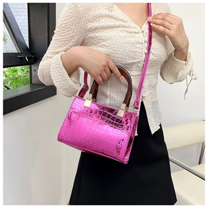 Detail of metallic pink crocodile pattern handbag with amber resin handles and silver buckle