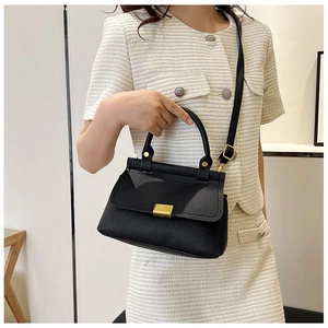 Close-up of black lychee texture handbag with elegant gold metal buckle and handle detail