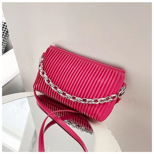 Detail of fuchsia pleated shoulder bag with silver chain handle and mirror reflection