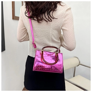 Detail of bright pink faux leather tote with crocodile pattern and amber resin handle