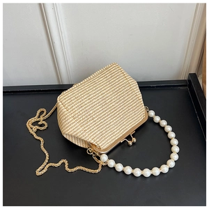 Détail du sac beige tissé avec poignée en perles et bandoulière en chaîne dorée