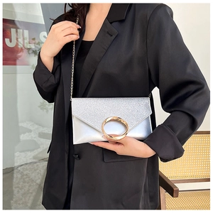 Detail of silver envelope clutch featuring sequin texture and large gold metal ring handle