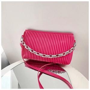 Detail of magenta pleated shoulder bag with silver chain on a reflective mirror surface