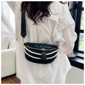 Détail du sac banane noir matelassé avec chaîne de perles sur une chemise blanche