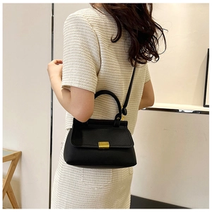 Detail view of black lychee grain crossbody bag with a gold buckle on a model
