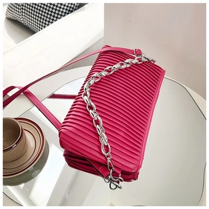 Detailed view of rose pink pleated shoulder bag with silver chain on mirror surface