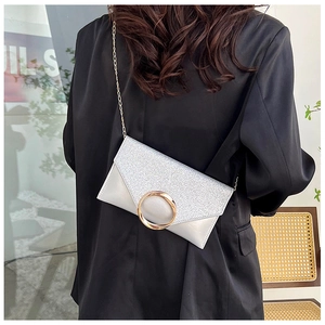 Close-up of silver glitter envelope clutch with gold ring buckle and chain strap