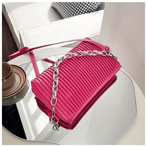 Detail of rose pink pleated crossbody bag with silver chain on mirror surface