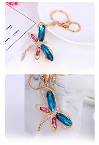Detail view of gold dragonfly keychain with blue crystal wings and lobster clasp