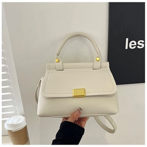 Detail of lychee textured cream handbag with golden rectangle clasp and rivet details