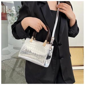 Detail of silver crocodile pattern handbag with tortoiseshell handles on a model