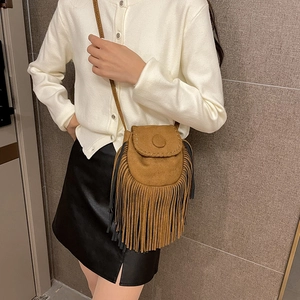 Brown suede crossbody saddle bag with decorative fringe and braided details on model