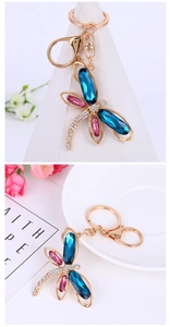 Detailed close-up of a gold dragonfly keychain with pink and blue crystal wings