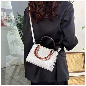 Detailed view of silver glossy crocodile pattern bag with brown round handles
