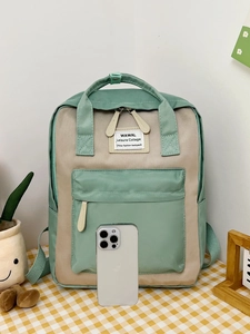 Detail of mint green and beige contrast nylon backpack with side pockets and front label