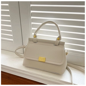 Close-up of pebble-grain cream faux leather bag with elegant gold rectangular clasp