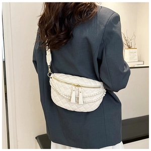 Détail d'un sac de poitrine blanc matelassé avec chaînes de perles et zips dorés
