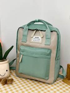 Detail of mint green and beige contrast backpack with multiple pockets on plaid surface