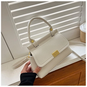 Detailed macro view of litchi texture cream leather handbag with gold metal lock