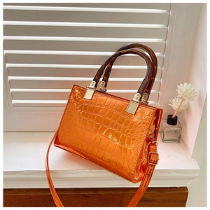 Detail of orange faux crocodile leather bag with tortoise shell handles and silver hardware