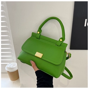 Detail of green litchi texture leather handbag with gold buckle and chain strap