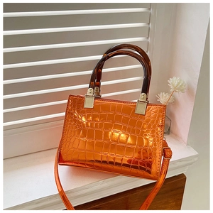 Detail of bright orange crocodile pattern handbag with resin tortoiseshell handles