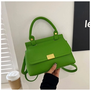 Detail of lime green pebbled leather handbag with golden buckle and chain accessories