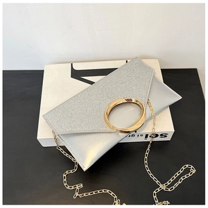 Detail of silver envelope clutch with glitter flap and golden circular metal handle