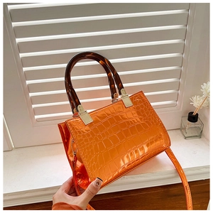 Detail of orange faux crocodile leather tote bag with tortoise shell acrylic handles