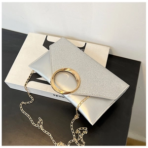 Detail view of silver envelope clutch bag with sequined flap and large gold metal ring clasp