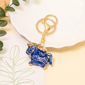 Detailed view of lucky horse keychain with blue enamel, gold edges, and faux pearls