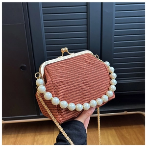 Détail du sac tissé rouge-brun avec poignée en perles et bandoulière dorée