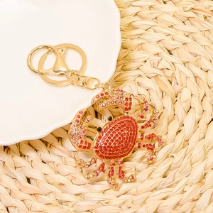 Detailed macro view of the gold crab keychain with sparkling red and aurora borealis crystals