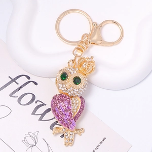 Close-up of golden owl keychain with purple rhinestone wings and crown detailing