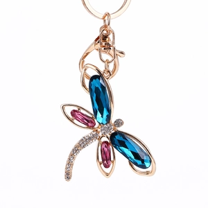 Golden dragonfly keychain with blue and pink crystals and white rhinestones on white background