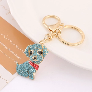 Détail d'un porte-clés chiot doré avec strass bleu ciel et nœud en émail rouge