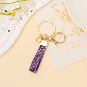 Dettaglio del cinturino in pelle glitterata viola e del portachiavi con chiusura dorata