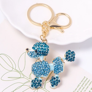 Detail of blue rhinestone poodle keychain with golden alloy lobster clasp on a white plate