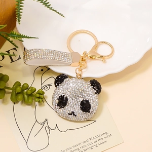 Detail eines Kristall-Panda-Schlüsselanhängers mit Strassband auf Dekoteller