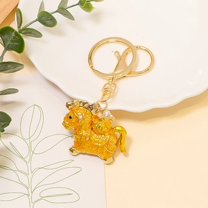 Close-up of golden horse keychain with traditional relief patterns and a pearl accent