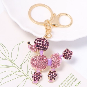 Macro shot of pink rhinestone poodle keychain with golden alloy lobster clasp on white tray