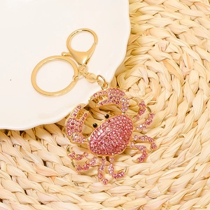 Detailed macro view of pink rhinestone crab keychain with polished golden hardware