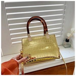 Detail of gold croc-effect handbag with tortoiseshell handles and adjustable strap