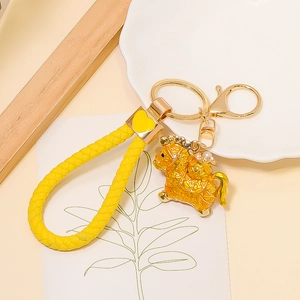 Detailed macro view of a golden horse pendant with yellow woven leather keychain strap