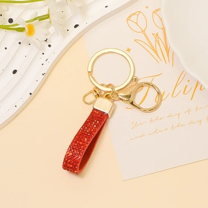 Dettaglio del portachiavi in pelle rossa glitterata con fibbia dorata e moschettone